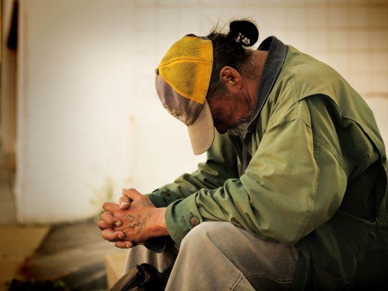 Homeless man sitting with his head bowed