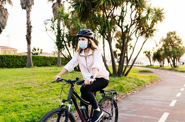 Woman wearing face mask rides bicycle.